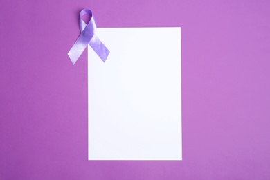 Purple awareness ribbon and blank card on color background, top view with space for text