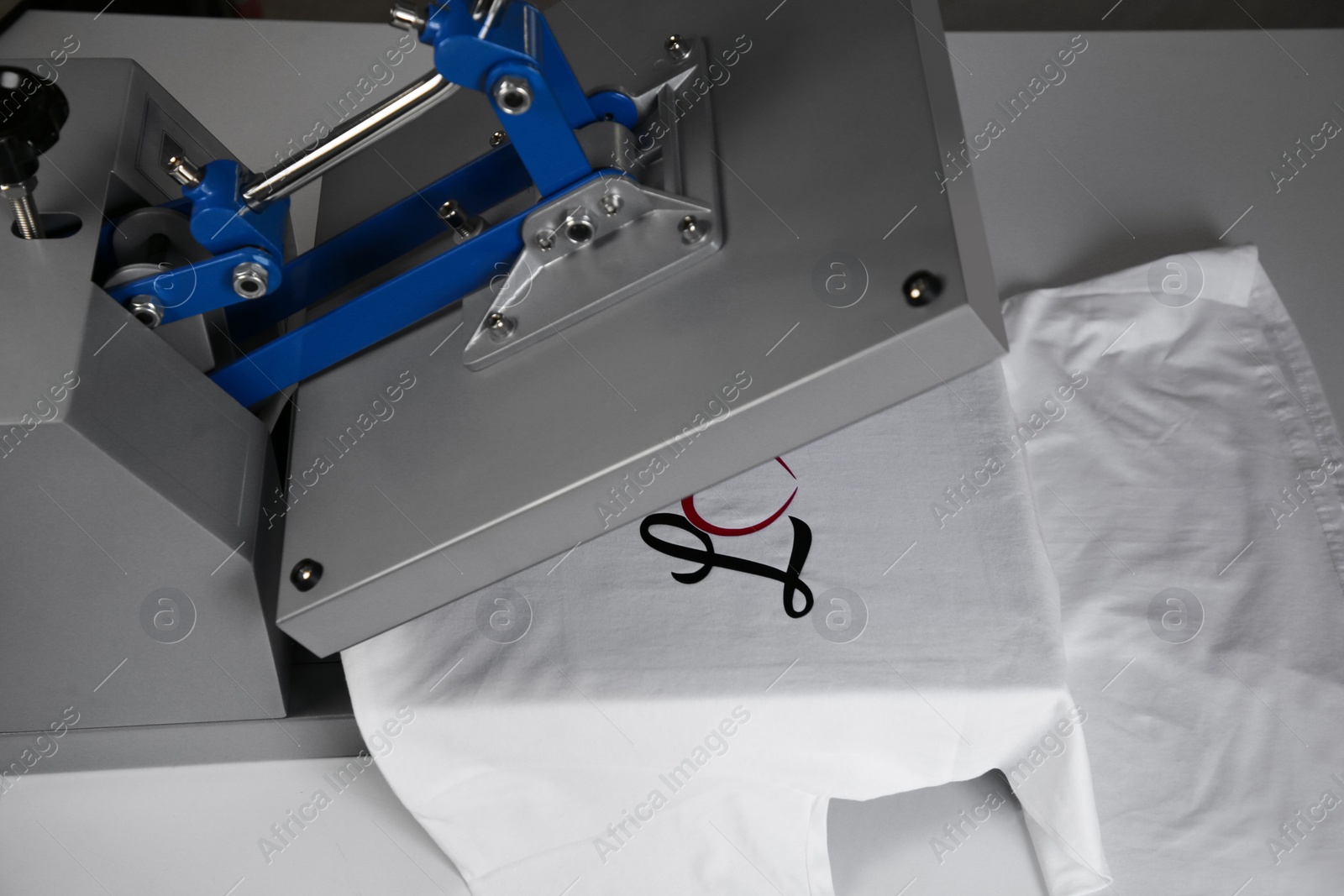 Photo of Printing logo. Heat press with t-shirt on white table