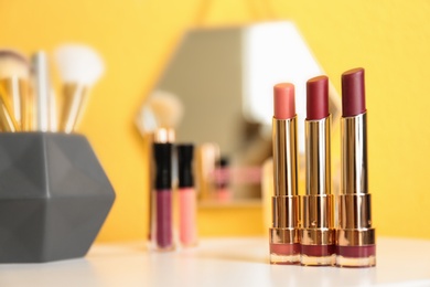 Bright lipsticks in gold tubes on dressing table, space for text