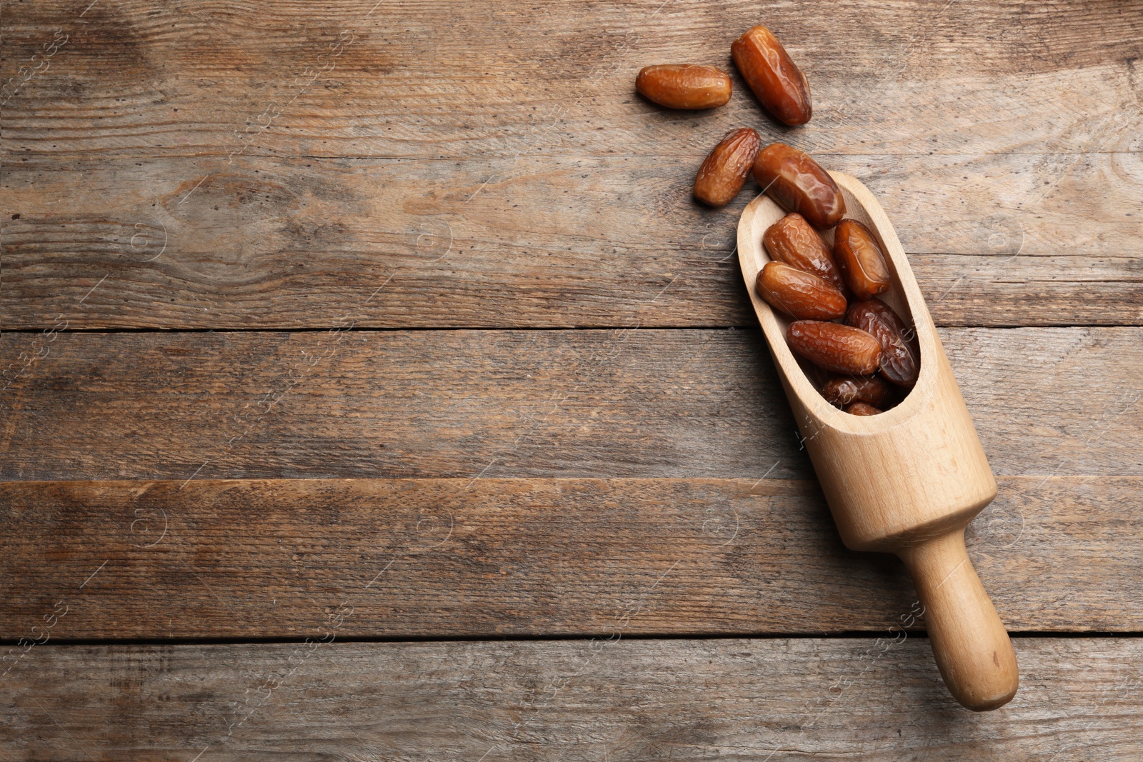 Photo of Scoop with sweet dried date fruits on wooden background, top view. Space for text