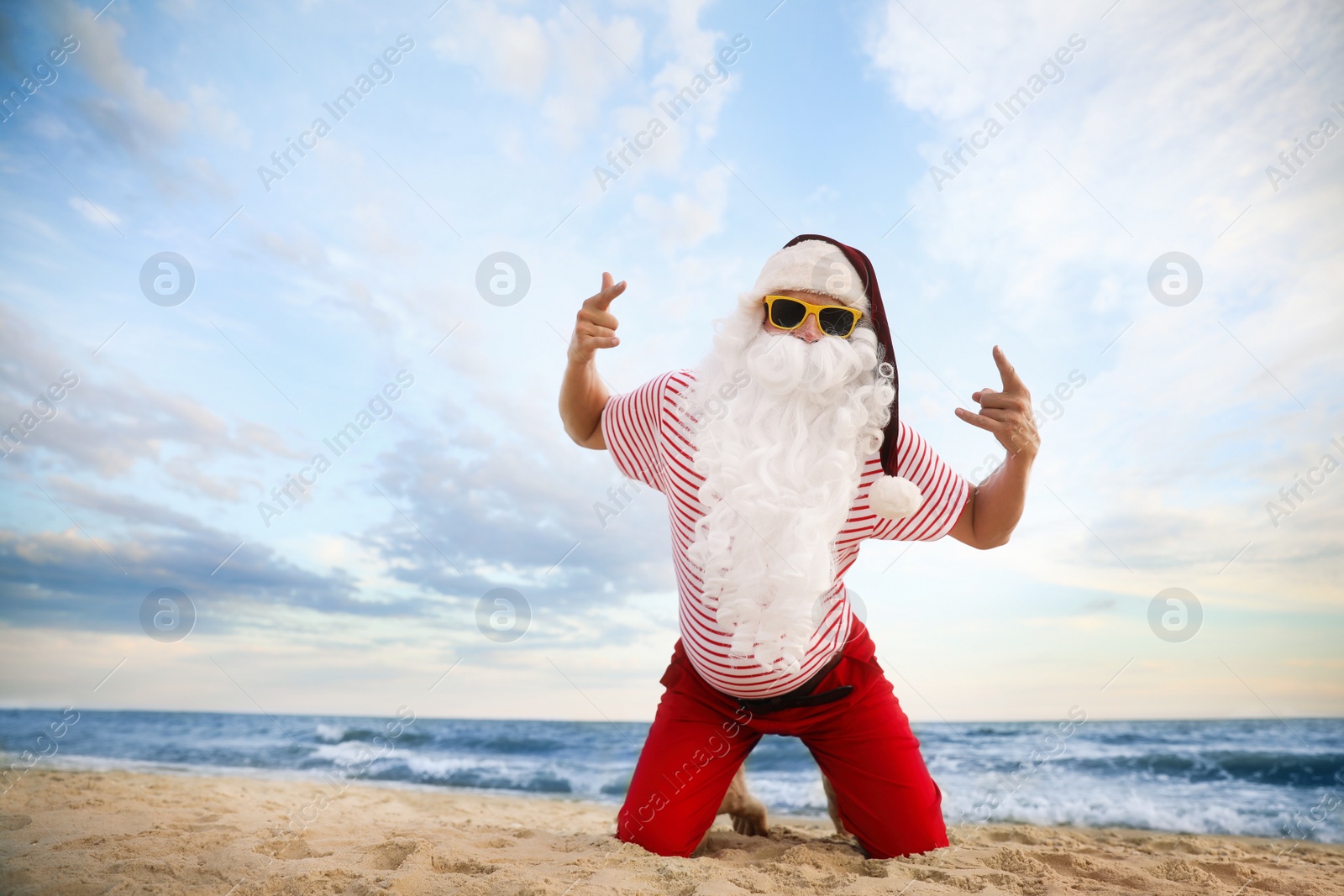 Photo of Santa Claus having fun on beach, space for text. Christmas vacation