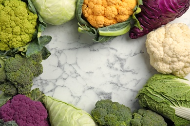 Different cabbages on marble table, top view. Healthy food