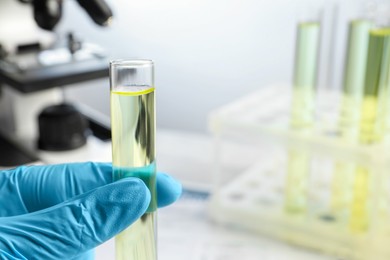 Photo of Doctor holding test tube with urine sample for analysis in laboratory, closeup. Space for text