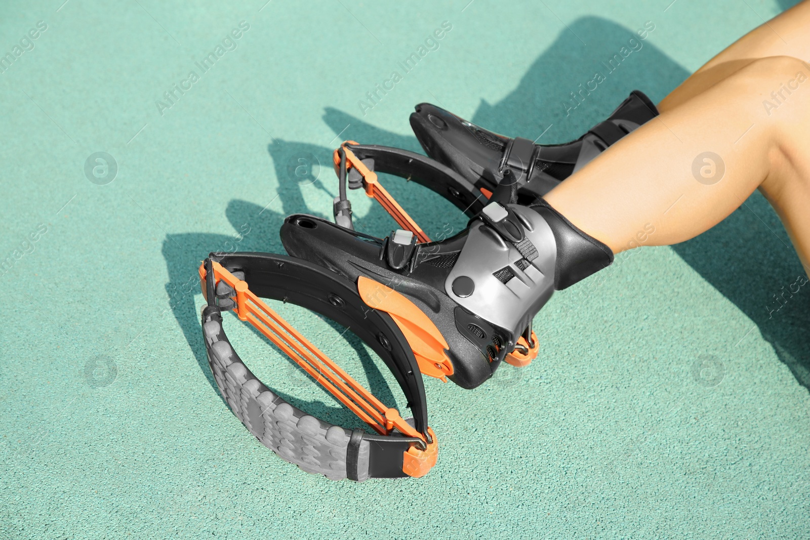 Photo of Woman with kangoo jumping boots on turquoise textured background, closeup