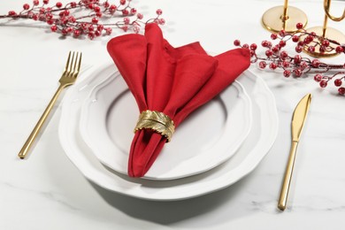 Photo of Stylish table setting with red fabric napkin, beautiful decorative ring and festive decor