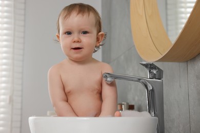 Photo of Cute little baby bathing in sink at home