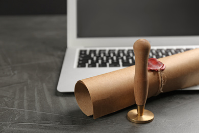 Photo of Notary's public pen and sealed document near laptop on grey stone table, closeup