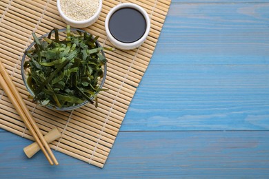 Photo of Fresh laminaria (kelp) seaweed served on light blue wooden table, flat lay. Space for text