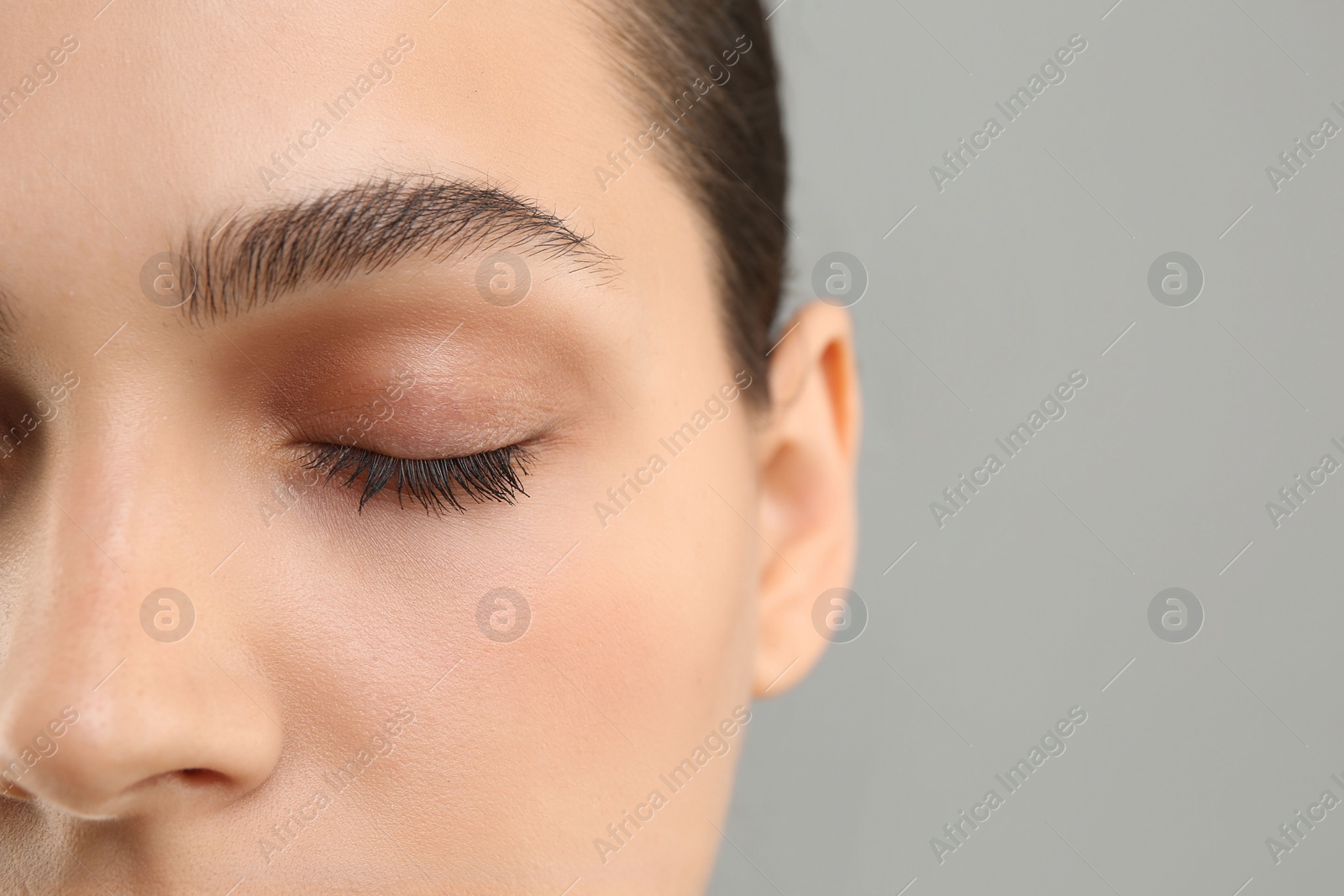 Photo of Young woman with perfect eyebrows on grey background, closeup. Space for text