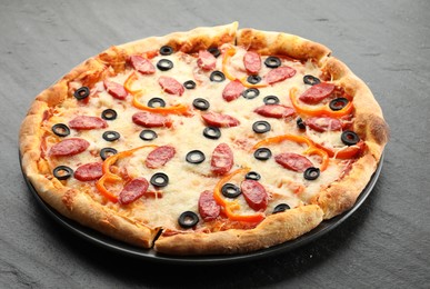 Tasty pizza with cheese, dry smoked sausages, olives and pepper on grey table