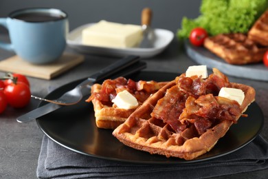 Photo of Tasty Belgian waffles served with bacon, butter and coffee on grey table, closeup