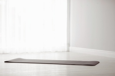 Photo of Rubber yoga mat on floor indoors. Space for text