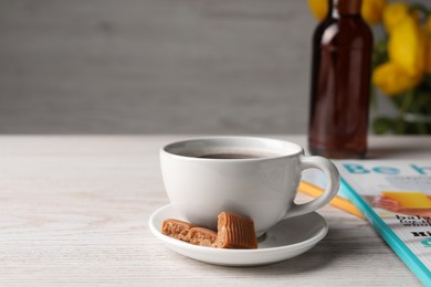 Photo of Cup of aromatic coffee, caramel candies and syrup on white wooden table