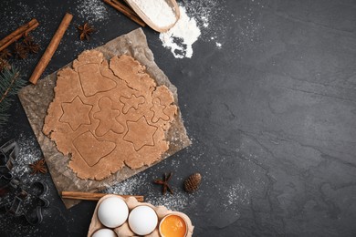 Photo of Making Christmas cookies. Flat lay composition with raw dough and ingredients on black table, space for text