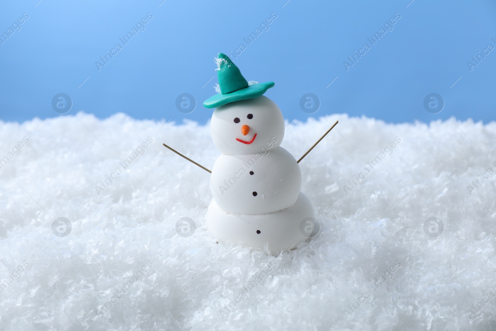 Photo of Funny snowman on snow against light blue background