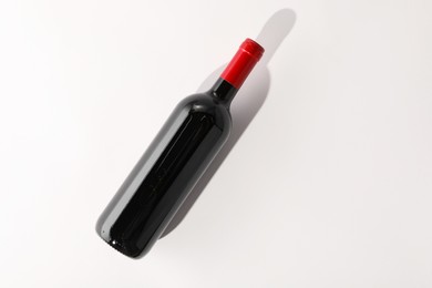 Bottle of expensive red wine on white background, top view. Space for text