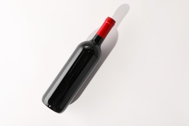 Photo of Bottle of expensive red wine on white background, top view. Space for text