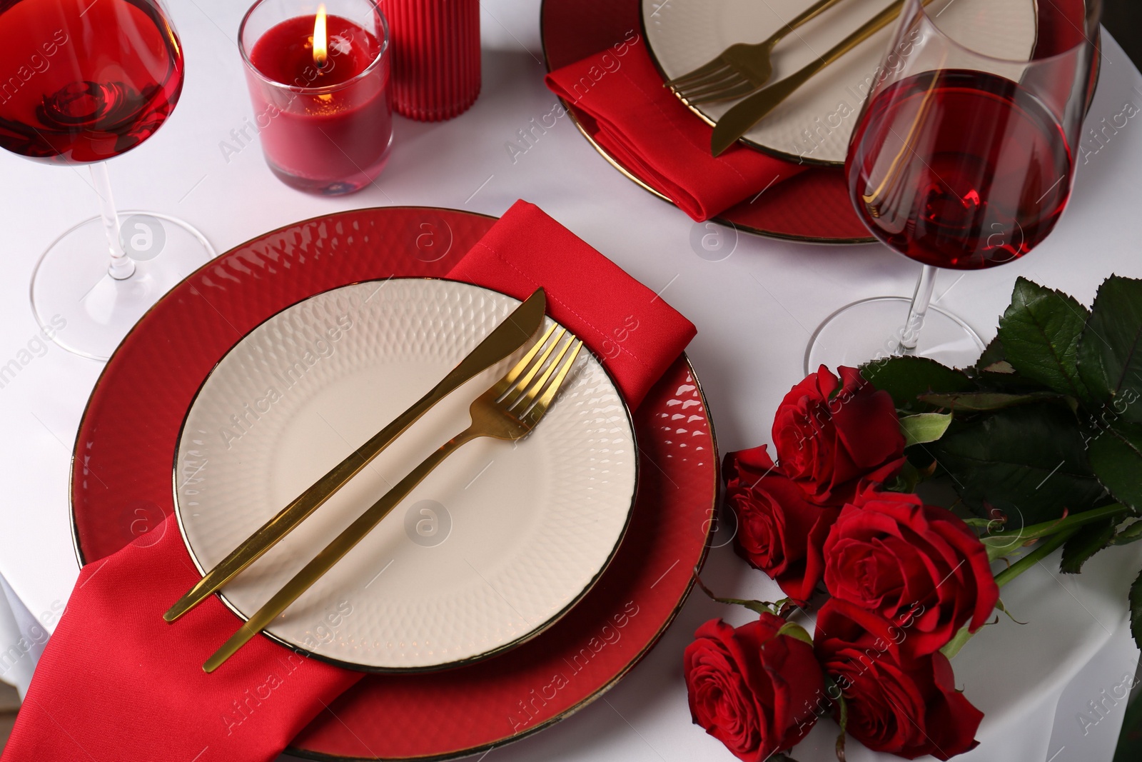 Photo of Place setting with roses and candle on white table. Romantic dinner