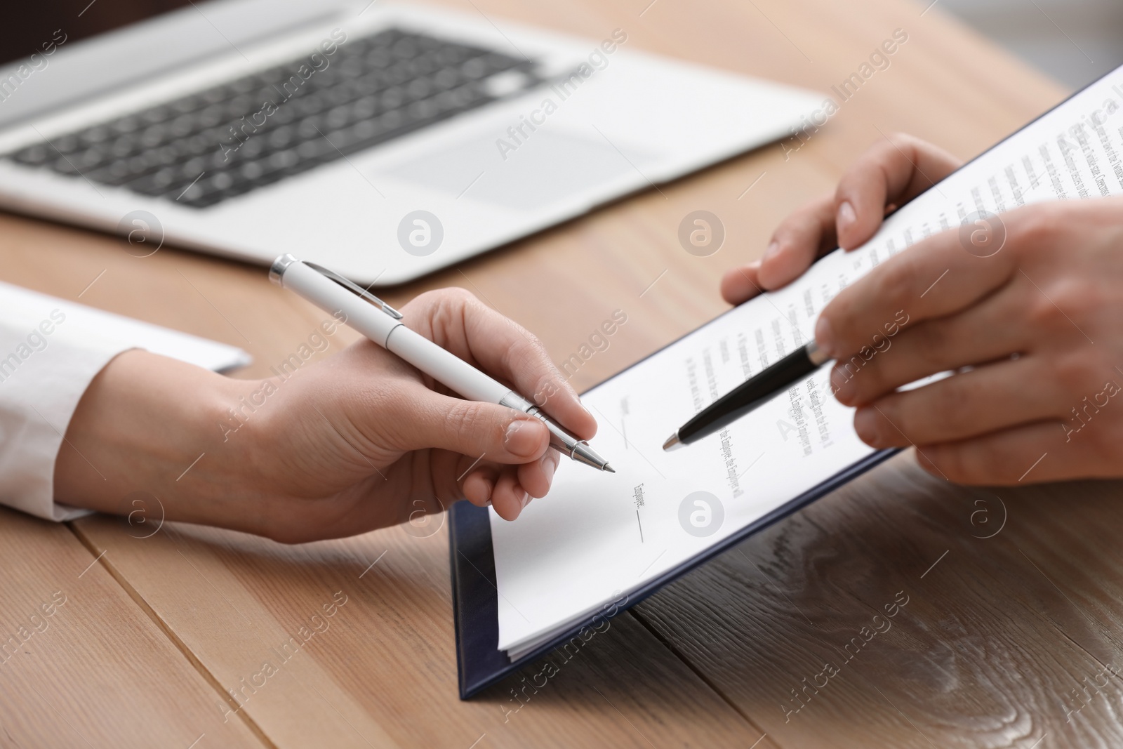 Photo of Businesspeople signing contract at wooden table, closeup