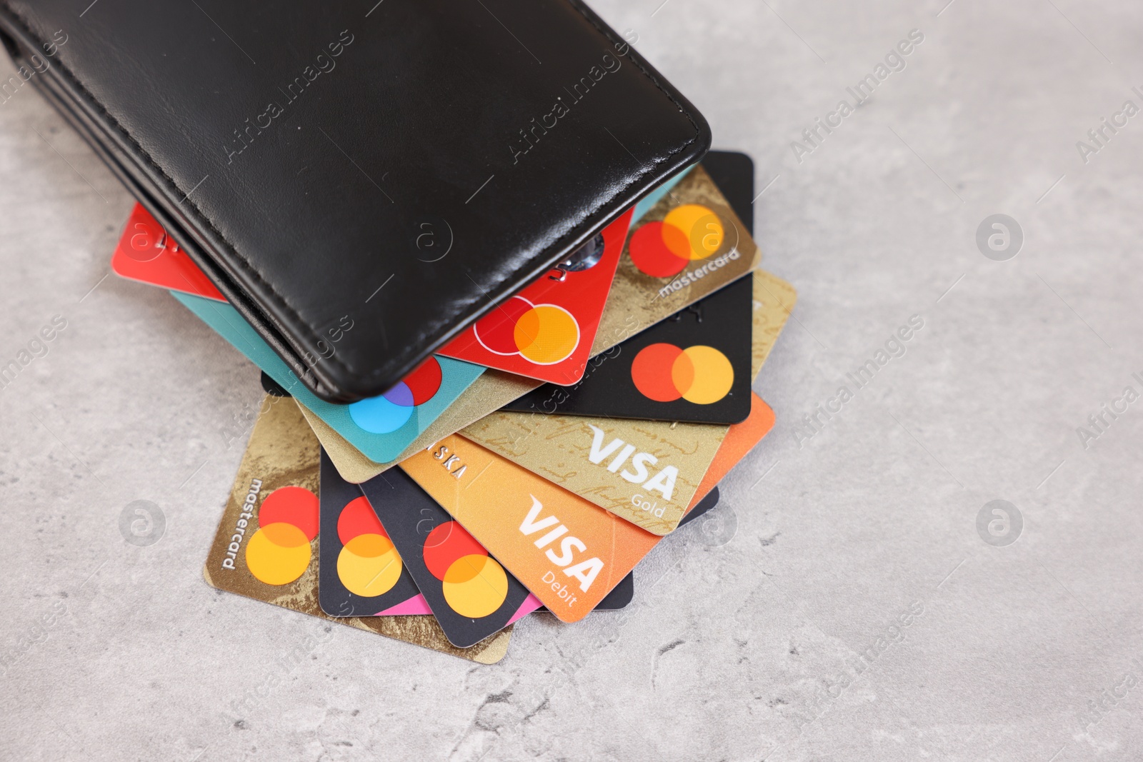 Photo of LEIDEN, NETHERLANDS - MARCH 07, 2024: Bank cards of Visa and Mastercard payment systems in leather wallet on light grey table