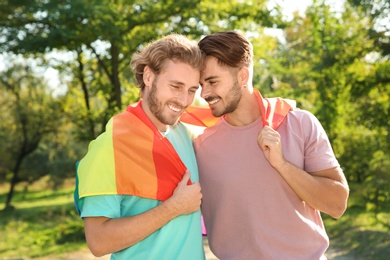 Happy gay couple with rainbow flag outdoors