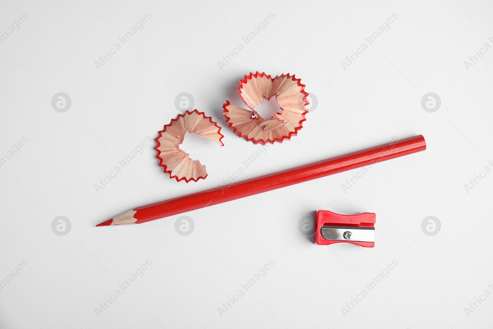 Photo of Color pencil, sharpener and shavings on white background, top view