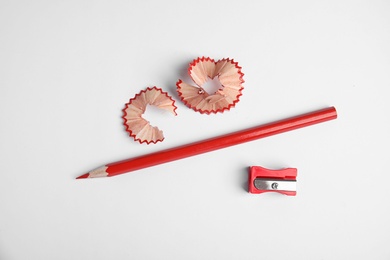 Photo of Color pencil, sharpener and shavings on white background, top view