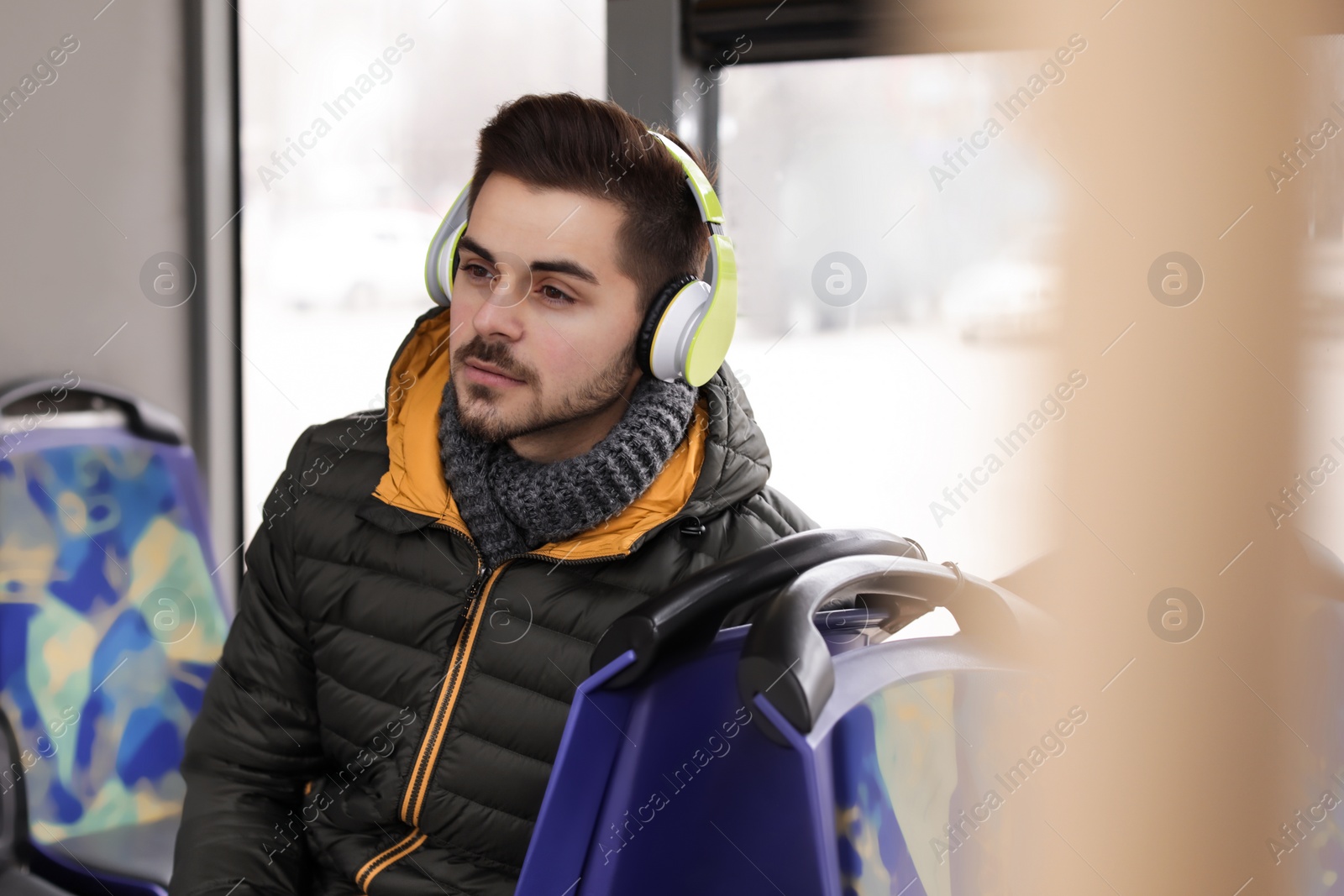 Photo of Young man listening to music with headphones in public transport