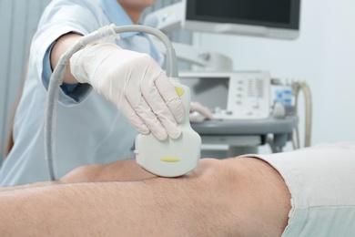 Doctor conducting ultrasound examination of patient's knee in clinic