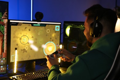 Photo of Man playing video games with controller at table indoors