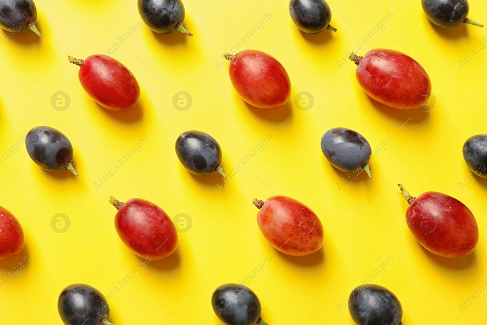 Photo of Fresh ripe juicy grapes on yellow background, top view