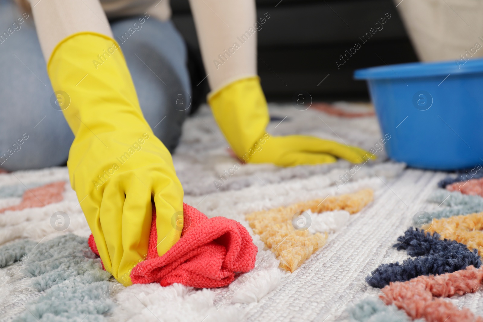 Photo of Woman in rubber gloves cleaning carpet with rag indoors, closeup