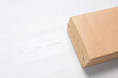 Parcel box wrapped in kraft paper on wooden background with space for text