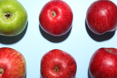 Photo of Ripe red and green apples on light blue background, flat lay