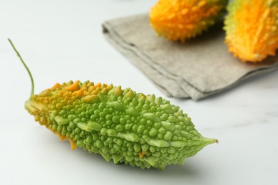Photo of Bitter melon on white marble table, closeup