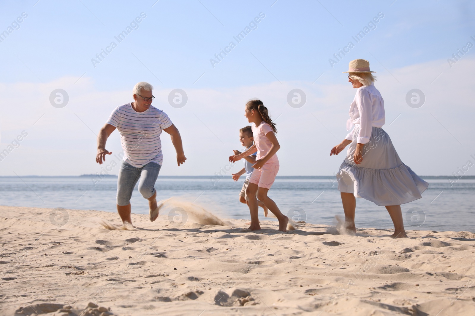 Photo of Cute little children with grandparents spending time together on sea beach