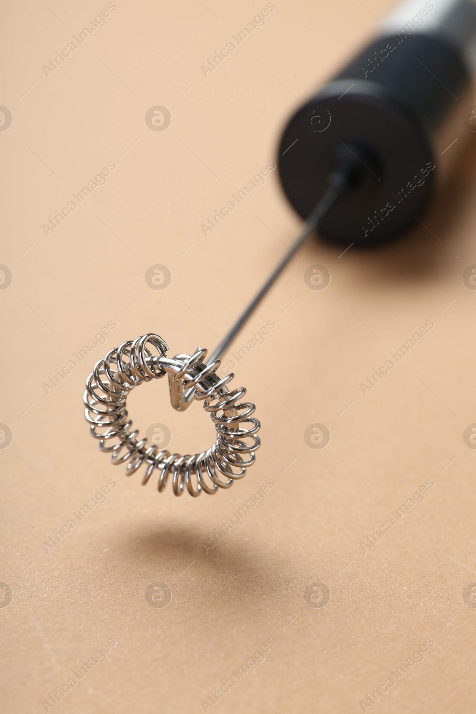 Photo of Milk frother wand on light brown background, closeup