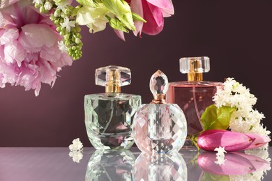 Photo of Luxury perfumes and floral decor on mirror surface against dark background