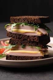 Photo of Delicious sandwiches with boiled sausage, cheese and arugula on grey table, closeup