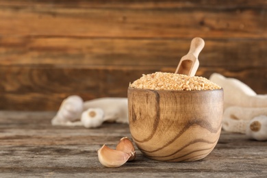 Bowl with granulated dried garlic on wooden table