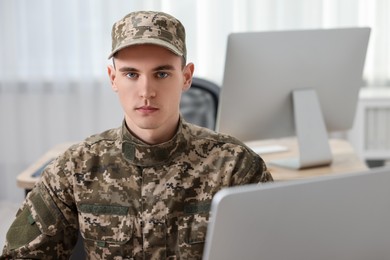 Photo of Military service. Young soldier working in office