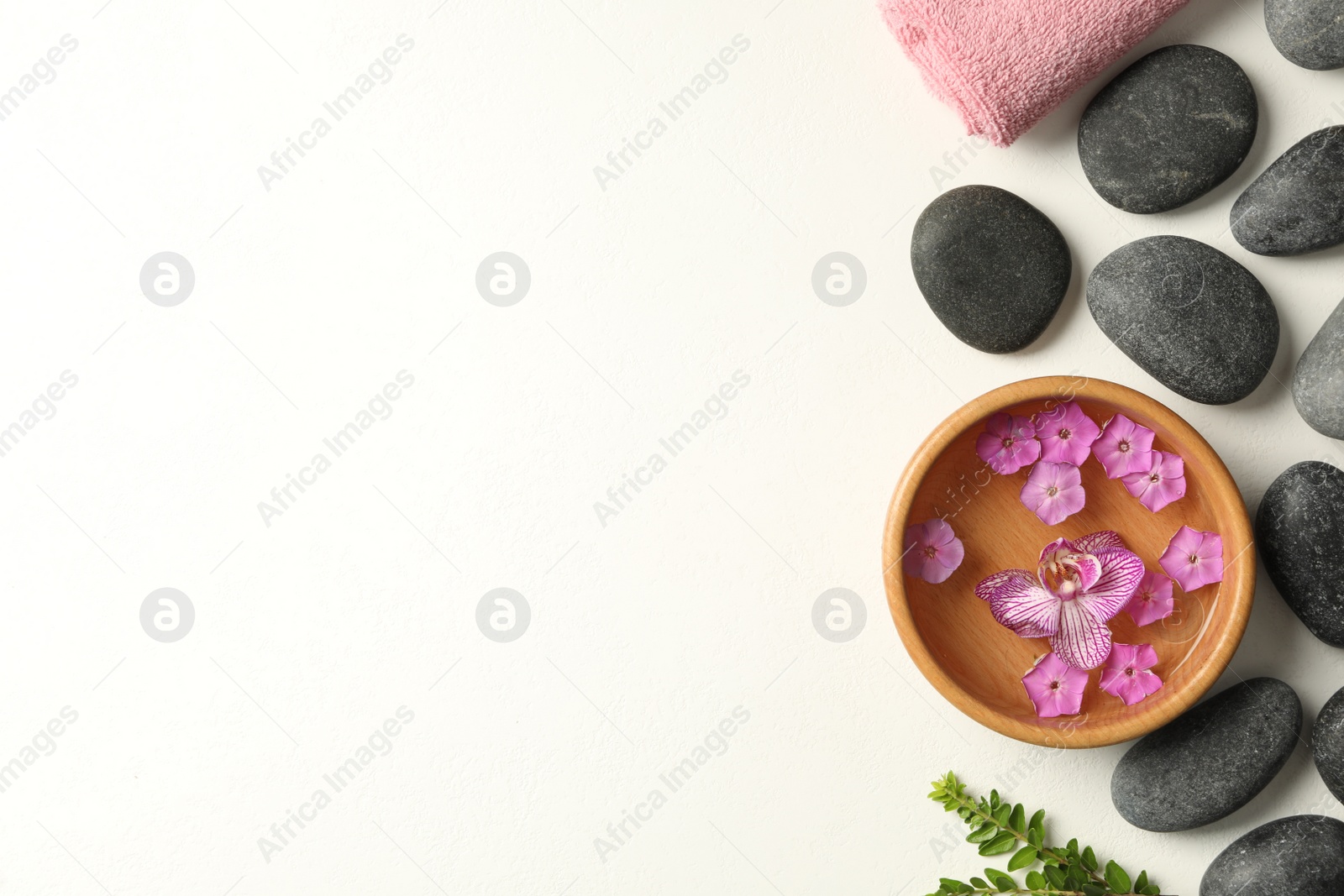 Photo of Flat lay composition with spa stones and flowers on white table. Space for text