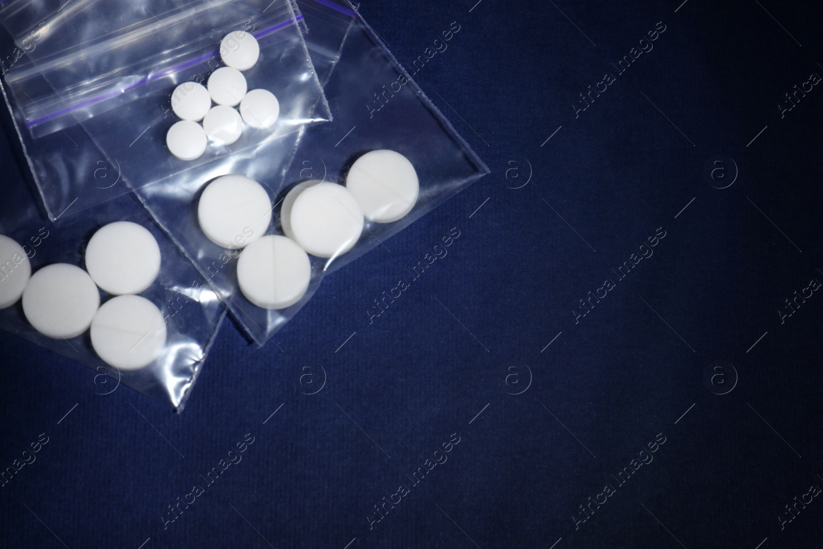 Photo of Ecstasy pills in plastic bags on color background, top view. Space for text