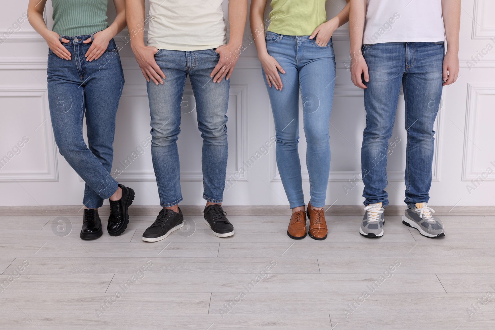 Photo of Group of people in stylish jeans near white wall indoors, closeup