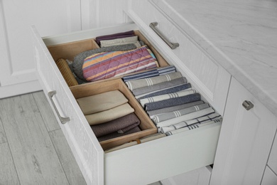 Photo of Open drawer with different textiles in kitchen