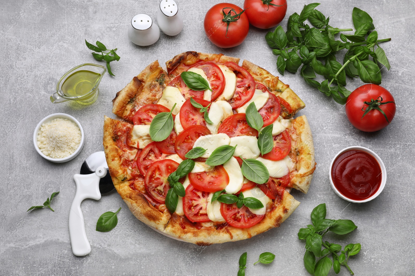 Photo of Delicious Caprese pizza with tomatoes, mozzarella and basil on light grey table, flat lay