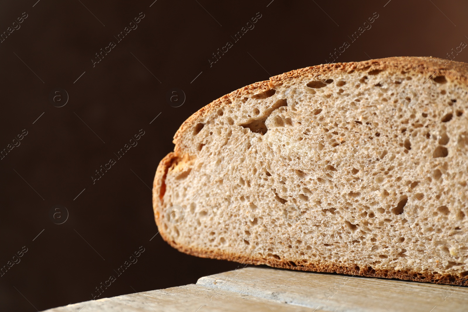 Photo of Piece of freshly baked sourdough bread on wooden table, closeup. Space for text