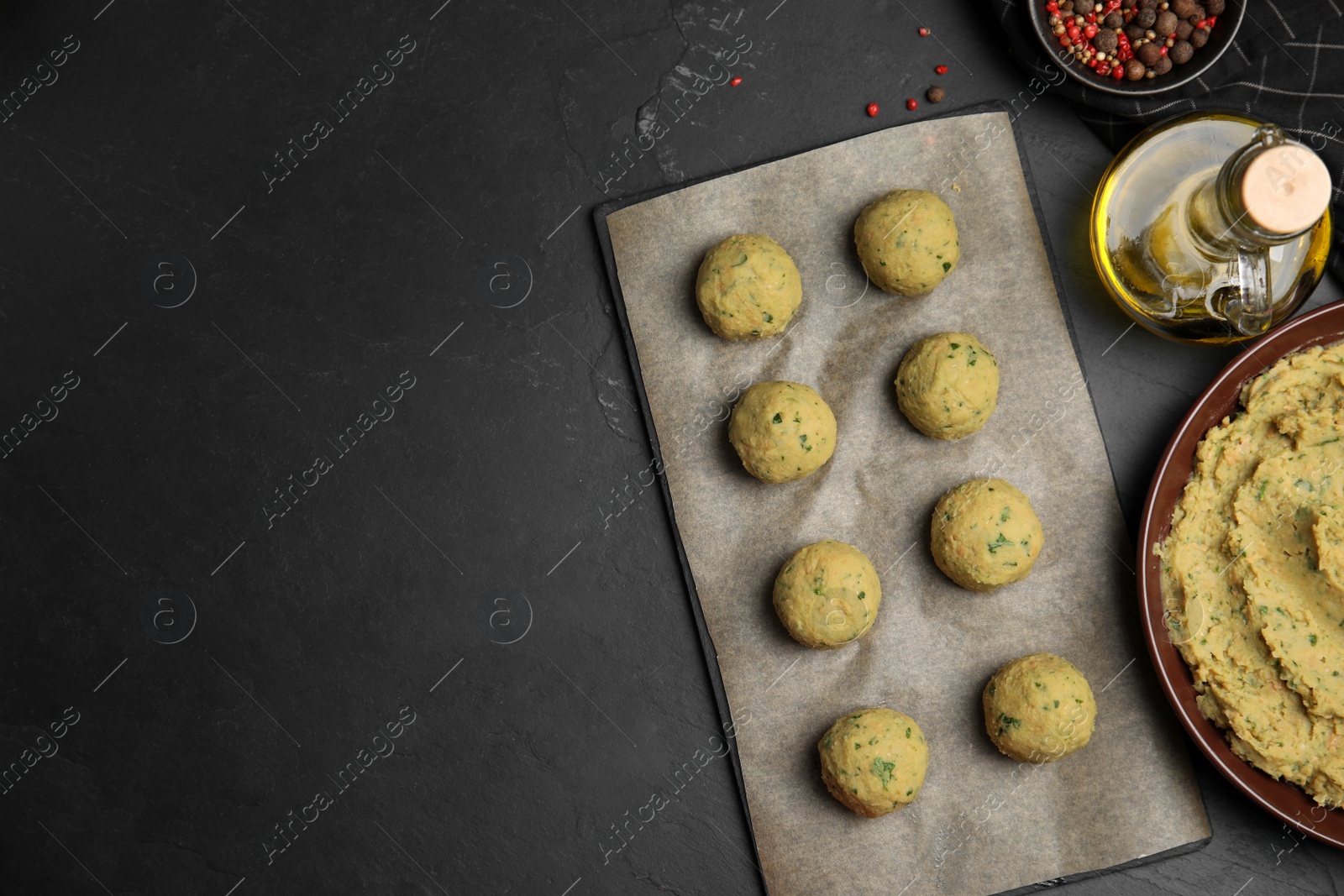 Photo of Raw falafel balls and ingredients on black table, flat lay. Space for text