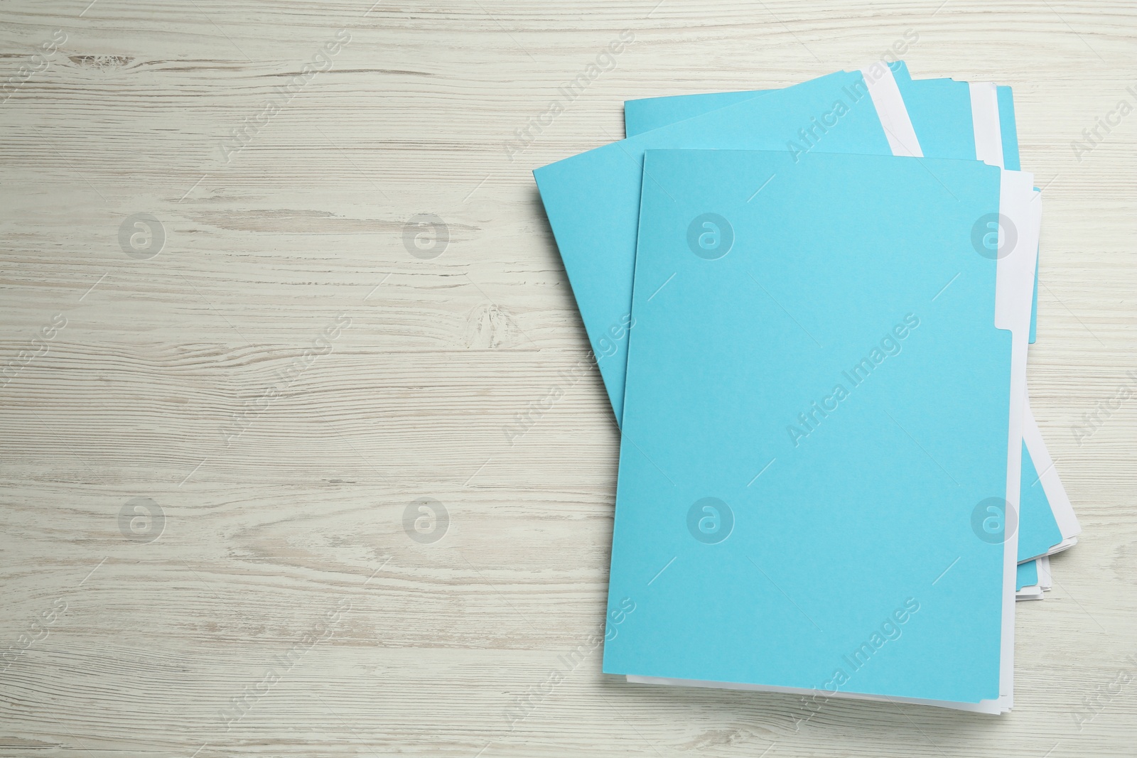 Photo of Turquoise files with documents on white wooden table, top view. Space for text