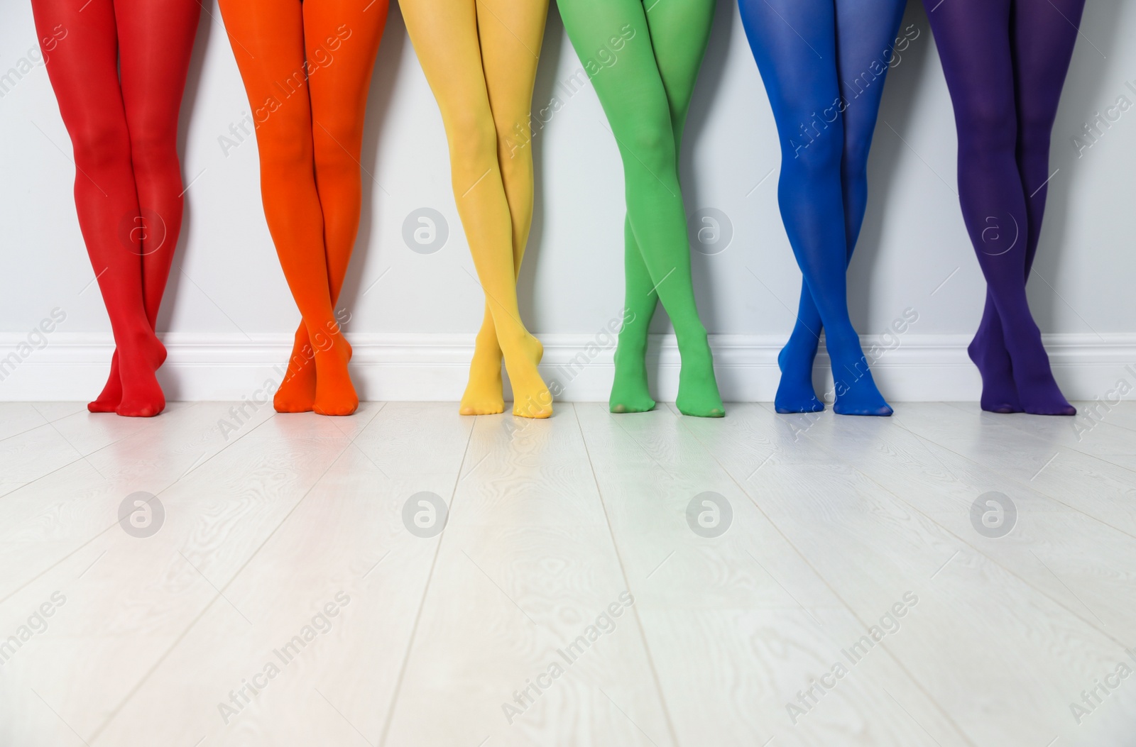 Photo of Women wearing colorful tights near white wall, closeup